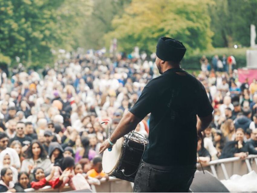A man playing a drum and facing a large audience