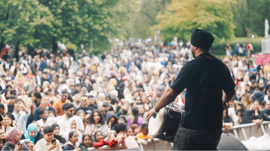 A man playing a drum and facing a large audience