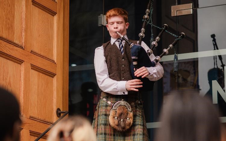 a young man in a kilt is playing the bagpipes