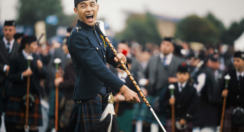 A man in a kilt shouts exuberantly. Blurred in the background is a large crowd - some of which are also kilted. Courtesy: Glasgow Life