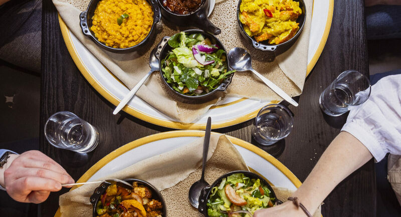 A round table laden with dishes of brightly coloured and delicious-looking food.