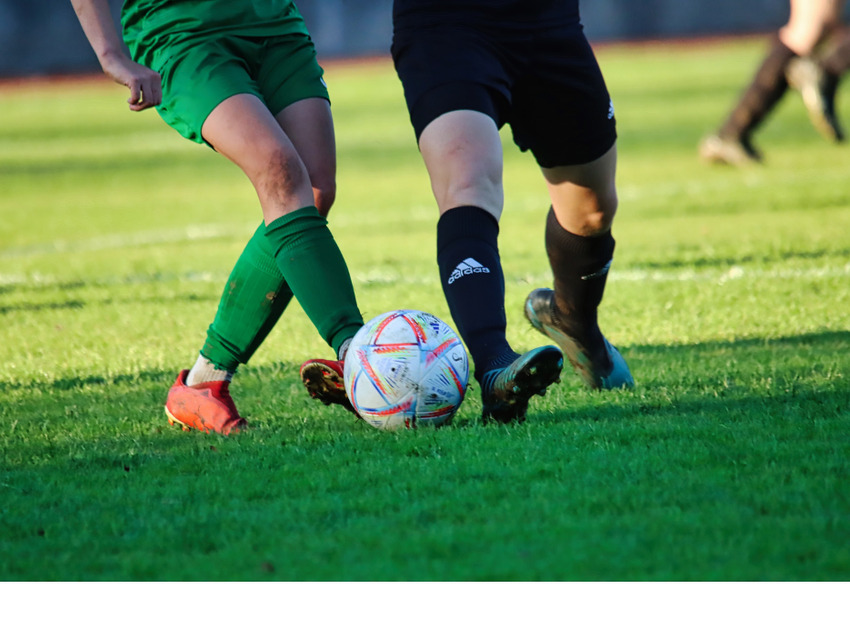 Two sets of legs in football boots challenge for the ball