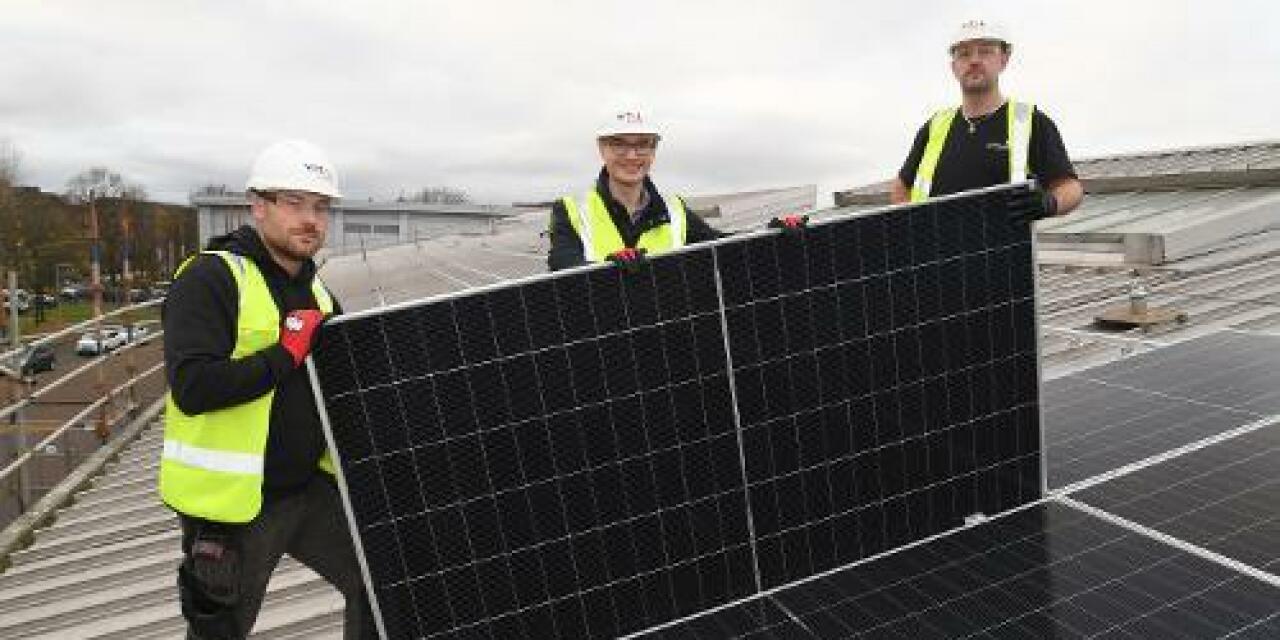 3 men in hi vis workwear are installing solar panels on a roof