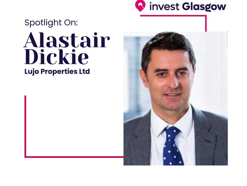 A man wearing a grey suit with a blue and white polka dot tie.